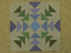 a piece of paper that has been cut into squares and triangles with green, blue, and purple colors