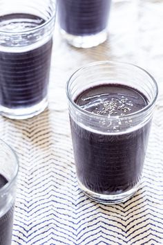 two glasses filled with dark colored liquid on top of a white and blue table cloth