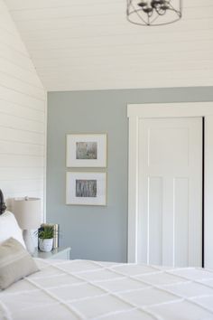 a white bed sitting in a bedroom next to two pictures hanging on the wall above it