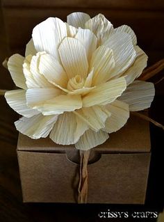 a large white flower sitting on top of a brown box with string wrapped around it