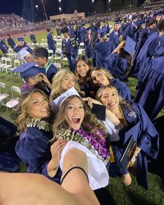 a group of young women in graduation gowns posing for a photo on the field