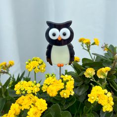 an owl figurine sitting on top of yellow flowers