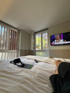 a person laying on top of a bed in front of a flat screen tv mounted to the wall