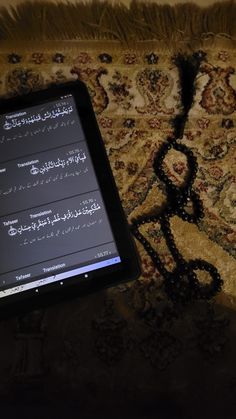 an electronic device sitting on top of a carpet next to a rug with arabic writing