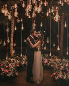 a bride and groom kissing in front of chandelier with hanging lights above them