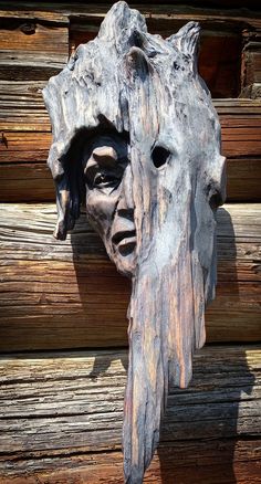 a wooden carving of a man's head on a wall made out of logs