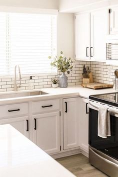 a kitchen with white cabinets and stainless steel appliances, including a dishwasher in the center