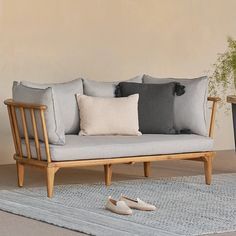 a couch with pillows and slippers on the floor next to a potted plant