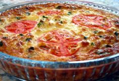 a tomato and cheese quiche in a glass dish on a counter top, ready to be eaten