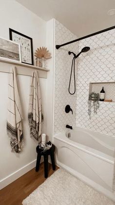 a white bathroom with black and white accessories on the shower head, rugs and towels