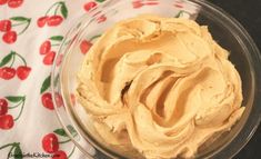 a glass bowl filled with peanut butter on top of a floral tablecloth covered table