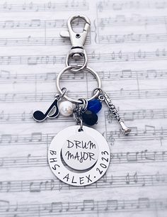 a keychain with music notes on it that says drum major, she's alex