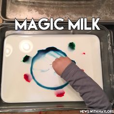 a young child is painting with watercolors on a white tray and the words magic milk above it