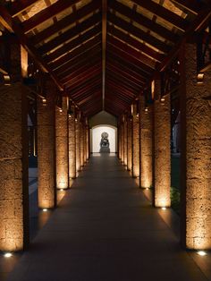 the walkway is lined with stone pillars and lit up by lights on either side of it