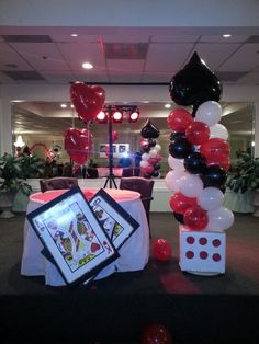 a table with balloons and pictures on it in the middle of a room filled with tables