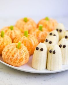 a plate topped with oranges and bananas cut in to look like jack - o'- lanterns