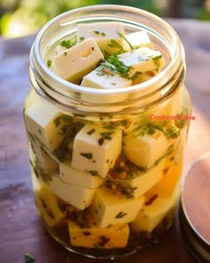 a jar filled with diced food sitting on top of a wooden table next to a container