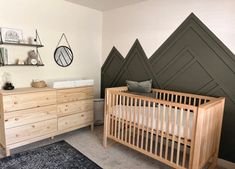 a baby's room with a crib, dresser and wall art on the walls