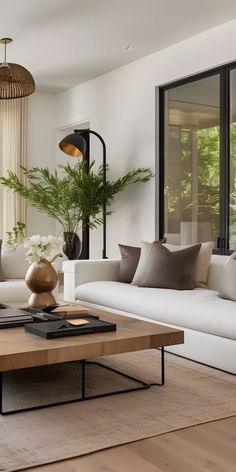 a living room with white couches and wooden tables in front of large glass windows