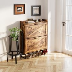 a wooden cabinet sitting on top of a hard wood floor next to a potted plant