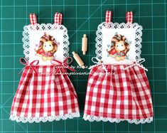 two red and white checkered aprons with teddy bears on them, one has a crayon pencil in it