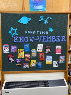 a bulletin board with pictures and magnets on it in a library area next to bookshelves