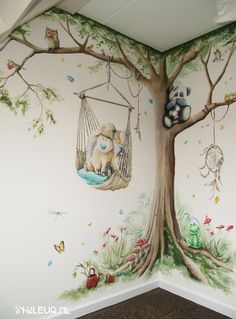 a child's room with a tree painted on the wall and stuffed animals hanging from it