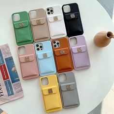 six cell phone cases sitting on top of a table next to a cup and vase