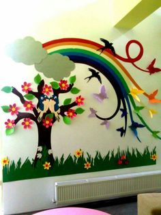 the wall is decorated with colorful paper cutouts and birds flying over trees, flowers, and rainbows