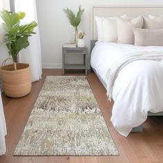 a white bed sitting next to a green plant on top of a hard wood floor