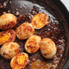 cooked eggs are in a skillet with brown sauce on the side, ready to be eaten