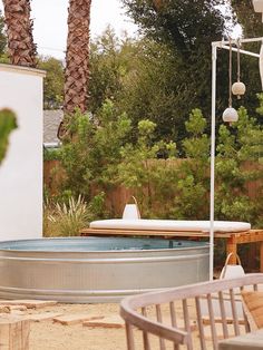 an empty hot tub in the middle of a backyard with palm trees and other outdoor furniture