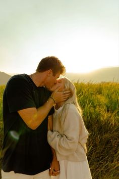 a man and woman kissing in the grass