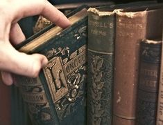 a hand is holding an old book in front of some books