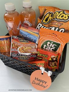 a basket filled with snacks and drinks on top of a white counter next to a sign that says happy birthday