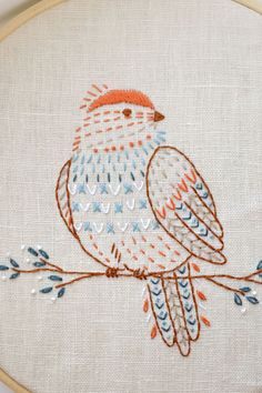 an embroidered bird sitting on top of a tree branch