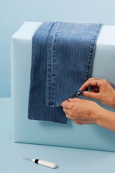 a person is using scissors to cut the fabric off of a piece of blue cloth