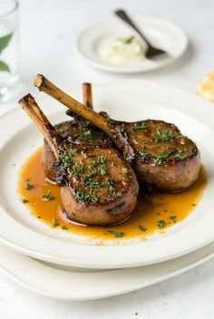 two steaks on a plate with sauce and garnish