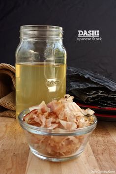 a glass bowl filled with food sitting on top of a wooden table next to a jar