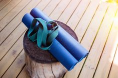 a rolled up blue yoga mat sitting on top of a wooden stump in the sun