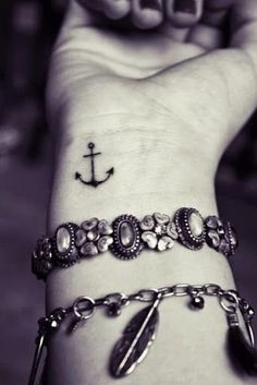 black and white photograph of a person's wrist with an anchor tattoo on it