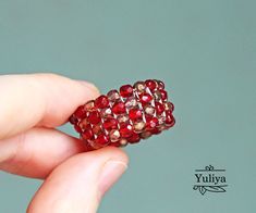 a person holding a red beaded ring in their hand