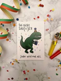 a birthday card with a dinosaur holding a present surrounded by confetti and streamers