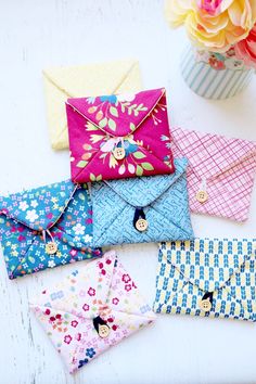 four envelopes sitting on top of a table next to a vase with flowers in it