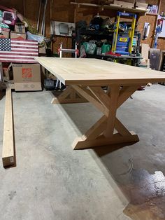 a wooden table sitting in a garage next to some boxes and other items on the floor