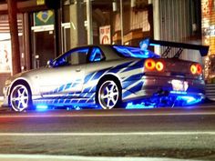 a silver car parked on the side of a street next to a tall building at night