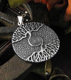 Material: 100% Sterling silver Weight: 6.4 grams Size: Almost 1-1/8 inch diameter (28 mm) Item number: wh286 With a spiral symbol interwoven into its design, this dramatic pendant adds new meaning to the adage 'As Above So Below'. The trunk that supports the upper half of the tree joins with the trunk rising from the tree's roots, each curling itself into alternating layers of the spiral. The finally join together as a single point at the spiral's center. The crown (or top) of the tree and its c Spiral Sterling Silver Jewelry With Oxidized Finish, Spiral-shaped Engraved Sterling Silver Jewelry, Engraved Sterling Silver Spiral Jewelry, Unique Silver Spiral Necklace, Symbolic Spiral Sterling Silver Jewelry, Spiritual Silver Jewelry With Artistic Design, Silver Spiritual Jewelry With Artistic Design, Silver Jewelry With Artistic Design In Round Pendant, Silver Jewelry With Artistic Design Round Pendant