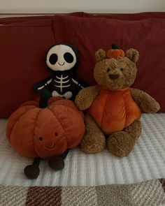 two stuffed animals sitting on top of a bed next to each other in front of a pillow