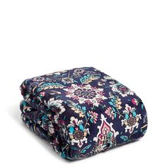 a blue and pink floral print blanket on top of a white surface with a black background