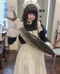 a woman dressed as a maid holding a fish in one hand and a knife in the other